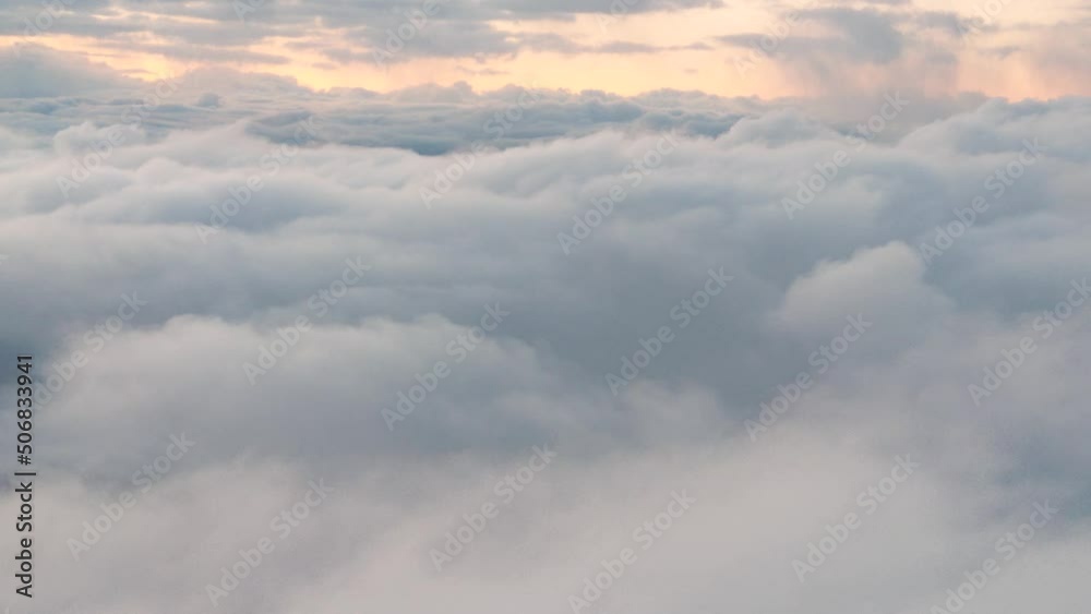 Dense clouds pass quickly past the airplane view, golden light illuminates the background, aerial view Dense clouds pass quickly past the airplane view, golden light illuminates the background, aerial view