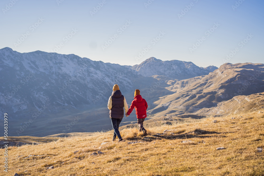 Fototapeta premium Montenegro. Mom and son tourists in the background of Durmitor National Park. Saddle Pass. Alpine meadows. Mountain landscape. Travel around Montenegro concept