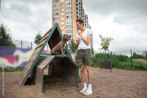 Male handler training dog outdoors on grassy playground