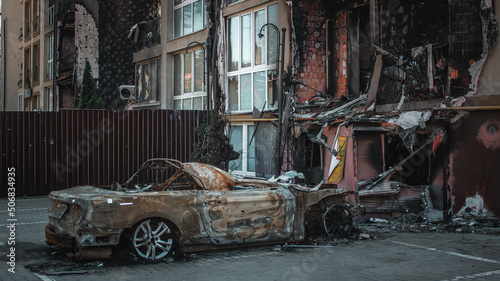 Obraz na płótnie Irpin, Kyiv Oblast, Ukraine - 19.05.2022: Cities of Ukraine after the Russian occupation. burnt civilian car near destroyed building in city of Irpin, northwest of Kyiv w salonie