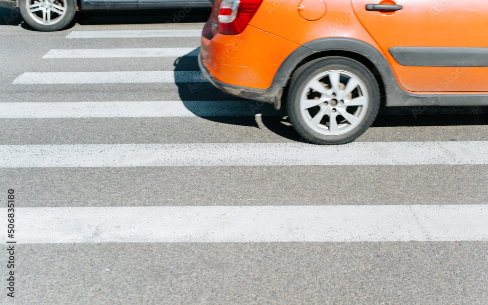 Fototapeta premium Side view of car driving on crosswalk outdoors. Close-up, selective focus on markings
