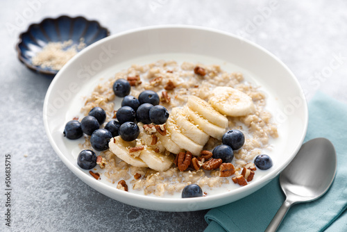 Oatmeal porridge with banana, blueberries, pecan nuts and sesame seeds photo