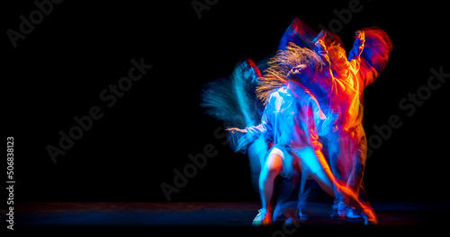 Dance show. Flexible man and girl, hip-hop dancers in motion and action isolated on dark background at dance hall in blue mixed neon light. Youth culture, hip-hop, movement