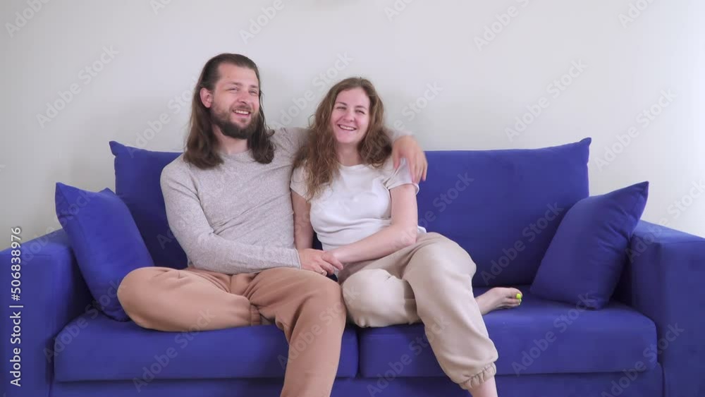 come to hug. couple is sitting on couch hugging and kissing. Kiss of two lovers on blue sofa. Caucasian man and woman in a cozy house spend time and weekends together. Be happy with each other. Smile. come to hug. couple is sitting on couch hugging and kissing. Kiss of two lovers on blue sofa. Caucasian man and woman in a cozy house spend time and weekends together. Be happy with each other. Smile.