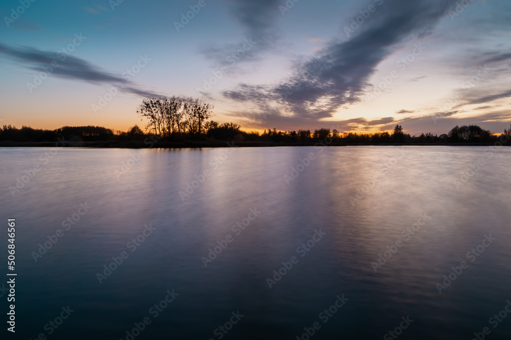Obraz premium Evening colourful clouds after sunset over a calm lake