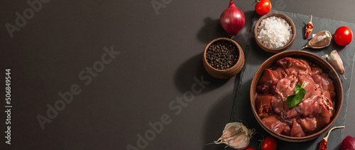 Raw chicken liver in a bowl. Fresh food ingredient and spices, trendy hard light, dark shadow photo