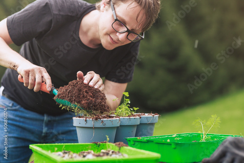 Gardener growing herbs in pots to have fresh herbs in his container herb garden. Water your potted herb garden or if you will be away on vacation,
