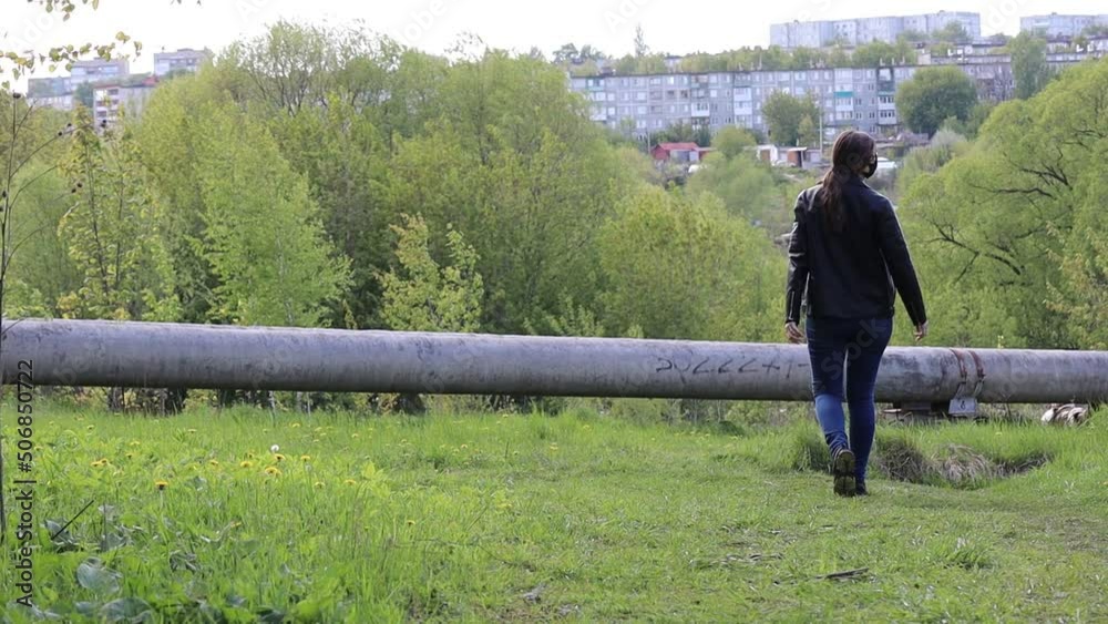 The girl walks along a narrow path in the park and turns around. Girl in a black mask and sunglasses The girl walks along a narrow path in the park and turns around. Girl in a black mask and sunglasses