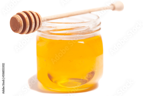Honey dripping from honey dipper in glass jar. Healthy food concept