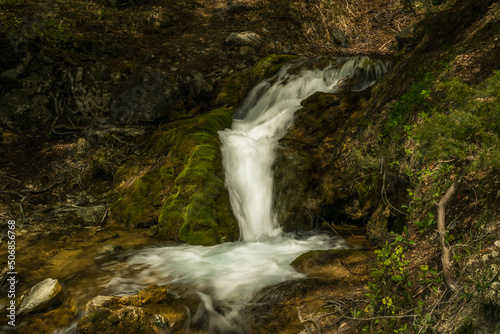 waterfall in the mountains with moss and rocks around