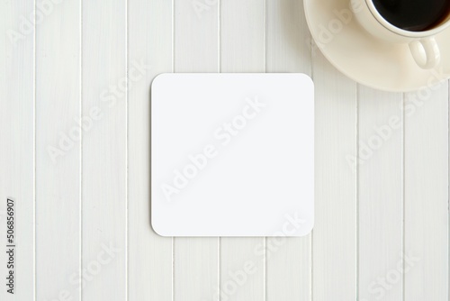 White blank square coaster mockup for design presentation on white wooden table. photo