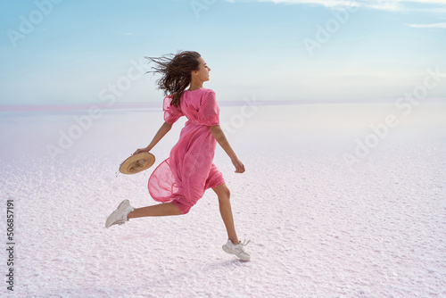 Bilde på lerret Running carefree woman on inspiring landscape of salt flats on pink lake