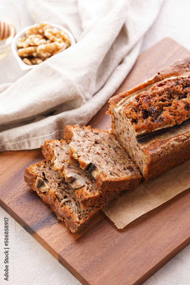 Chocolate banana bread with walnuts on a wooden board and ingredients on a grey neutral background Chocolate banana bread with walnuts on a wooden board and ingredients on a grey neutral background