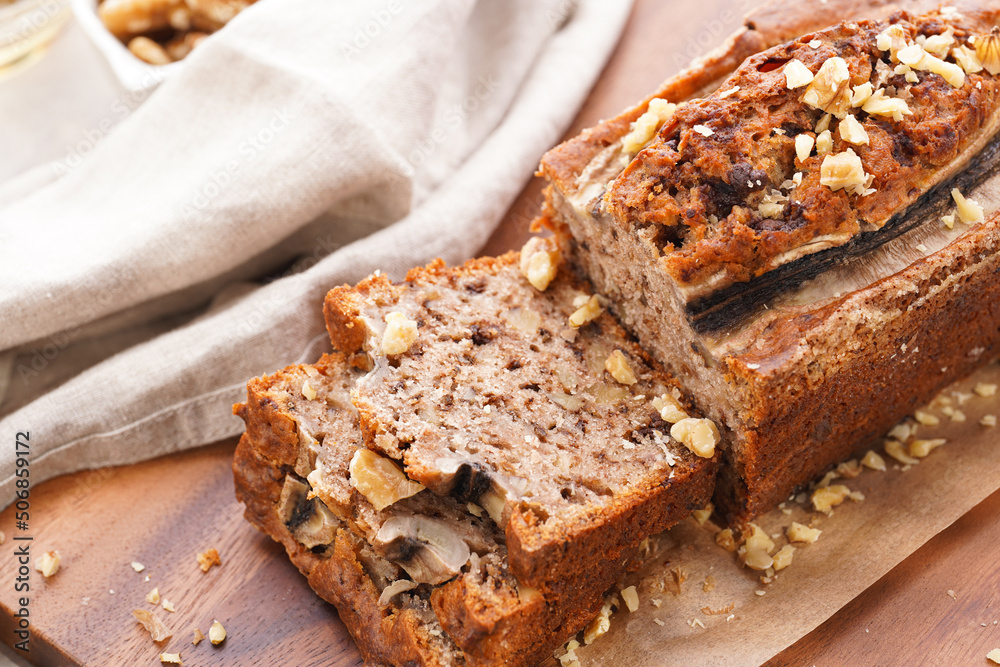 Chocolate banana bread with walnuts on a wooden board and ingredients on a grey neutral background