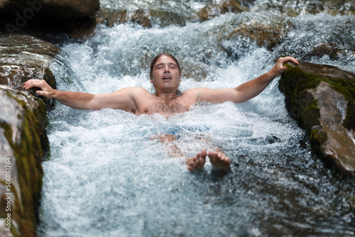 Mid Adult Man Taking a Ice Cold Bath in Wild Water Stream in Alps. Wim Hoff Method therapy of Breathing in Cold Environment