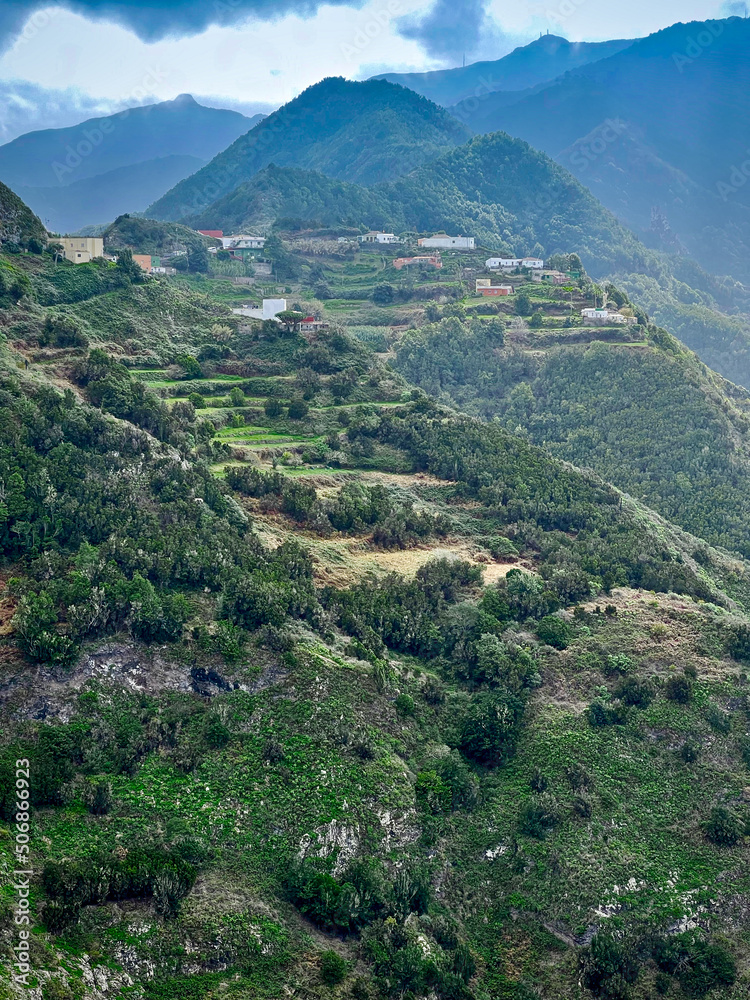 Volcanic mountains covered with tropical forests and an alpine village with terraces for agriculture