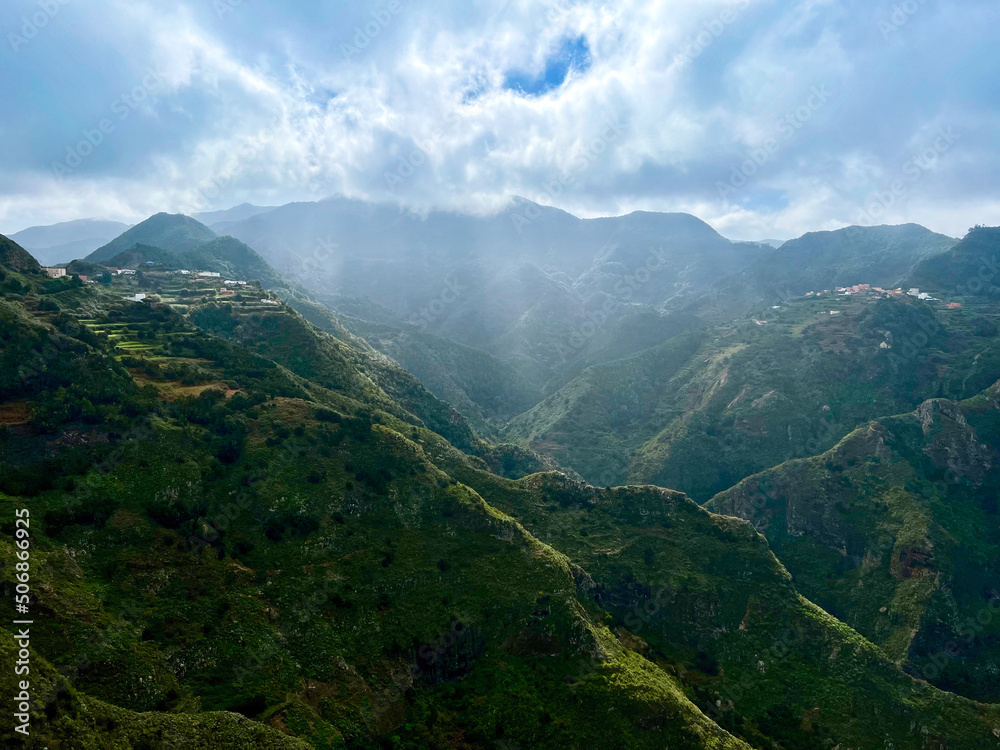 Volcanic mountains covered with tropical forests and an alpine village with terraces for agriculture Volcanic mountains covered with tropical forests and an alpine village with terraces for agriculture