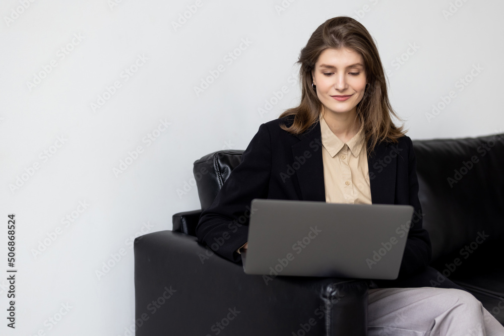 Smiling young woman using laptop, sitting on couch at home Smiling young woman using laptop, sitting on couch at home