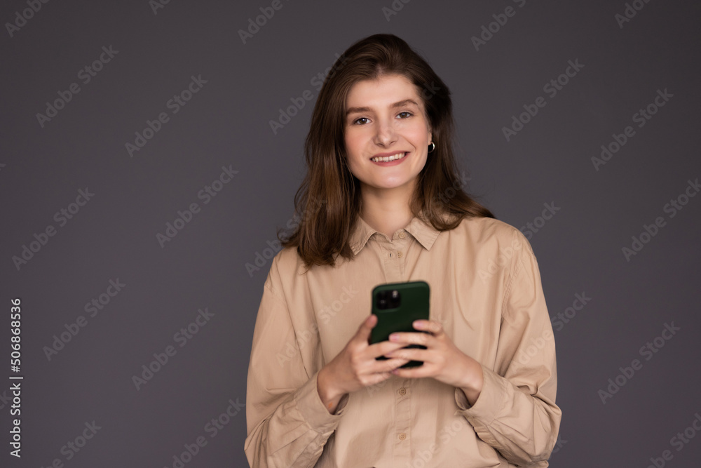 Portrait of a smiling casual woman holding smartphone over white background Portrait of a smiling casual woman holding smartphone over white background