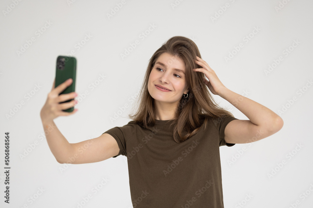 Portrait of a smiling woman making selfie photo on smartphone isolated on a white background Portrait of a smiling woman making selfie photo on smartphone isolated on a white background