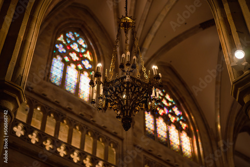 chandelier of the cathedral with the light of the stained glass windows reflecting on the back wall. 