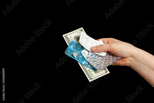 Hand holding money and empty pill packs on black background....