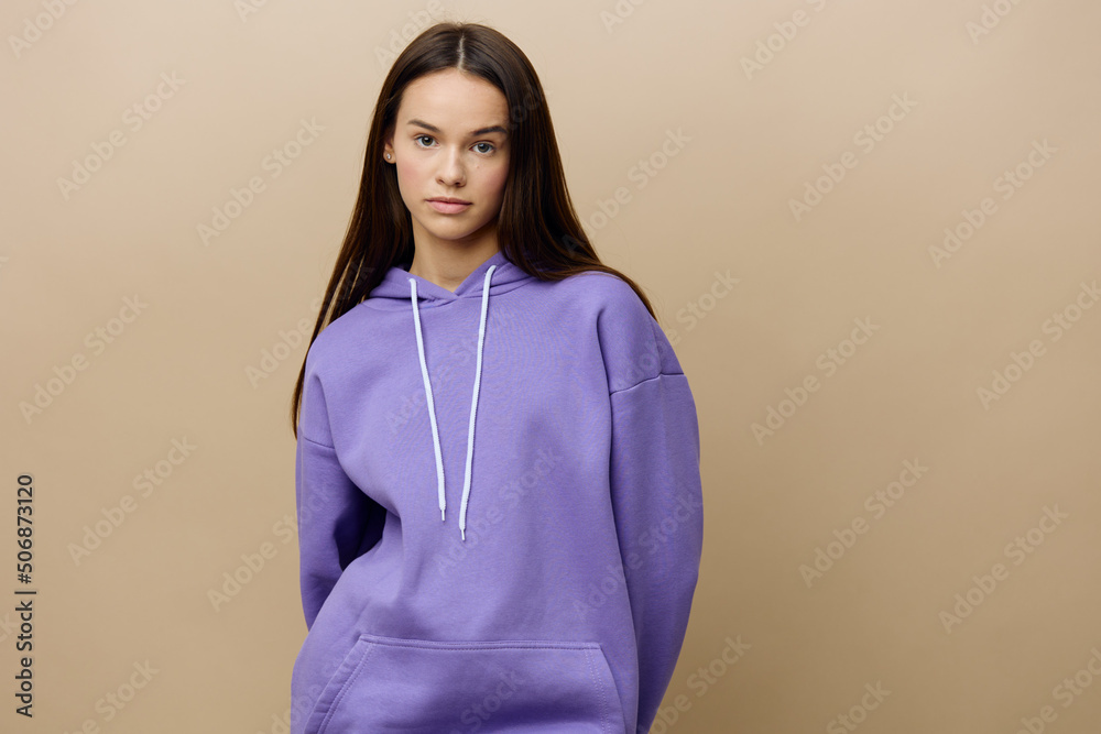 a happy, joyful, charming woman with long, loose, well-groomed hair poses on a beige background with an empty space for the insertion of an advertising layout