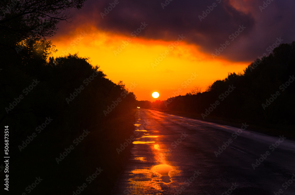 Road with puddles going into the distance at sunset Road with puddles going into the distance at sunset