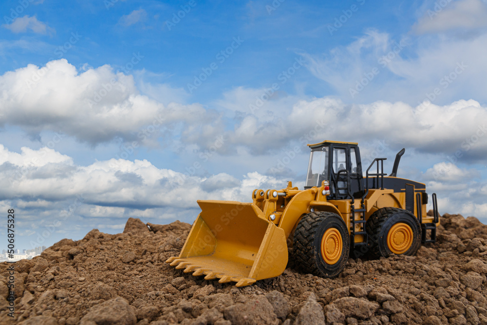 Wheel loader are digging the soil in the construction site on sky background ,with white fluffy cloud Wheel loader are digging the soil in the construction site on sky background ,with white fluffy cloud