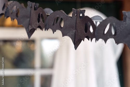 Black paper cut out garland in shape of flying bats.Burning lantern.Decorating of porch outdoor on street for halloween holiday.DIY home,street decoration,entertainment for children,horror atmosphere © velirina