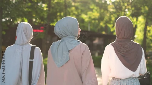 Rear view of three muslim women talking while walking outdoors photo