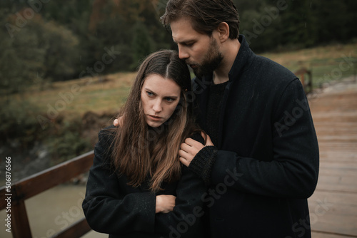 A young couple in love in black coats walks in the countryside in the rain. Autumn gloomy mood. cinematic image