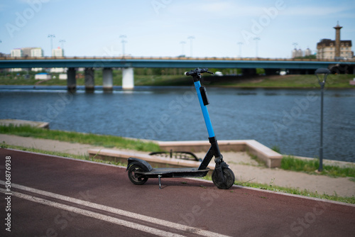 A blue electric scooter for rent is on the waterfront. High quality photo