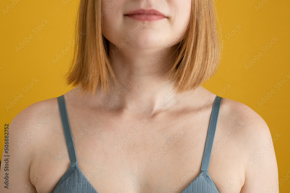 Anonymous young lady in bra standing against yellow background Anonymous young lady in bra standing against yellow background