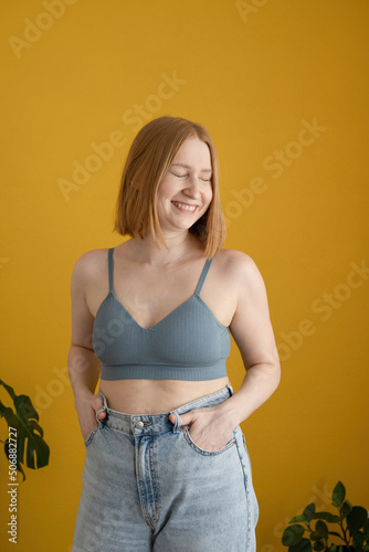 Positive young lady in bra smiling brightly with closed eyes photo