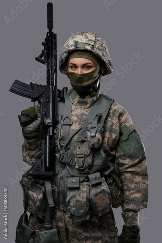 Portrait of proud army woman holding rifle dressed in protective camouflage uniform.