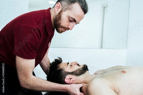 Male patient in physiotherapist's office with cervical and back pain