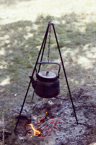 Travelers warm the water in a kettle on a fire from branches in the forest. Tourist's breakfast in nature