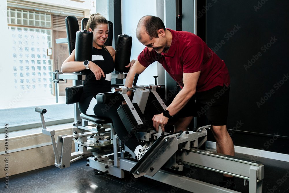 blonde girl working out with her personal trainer on a gym machine. blonde girl working out with her personal trainer on a gym machine.