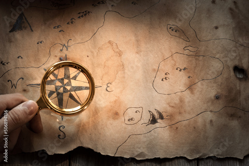 a man looks at an old map through a magnifying glass, the concept of travel and treasure hunting