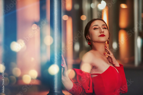 a glamorous woman in a red dress posing in the city