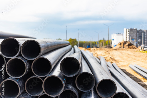 Water pipes for drinking water supply lie on the construction site. Preparation for earthworks for laying an underground pipeline. Modern water supply systems for a residential city. © Anoo