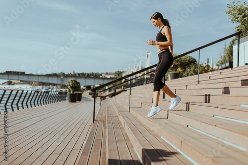 Young woman in sportswear exercising on a river promenade