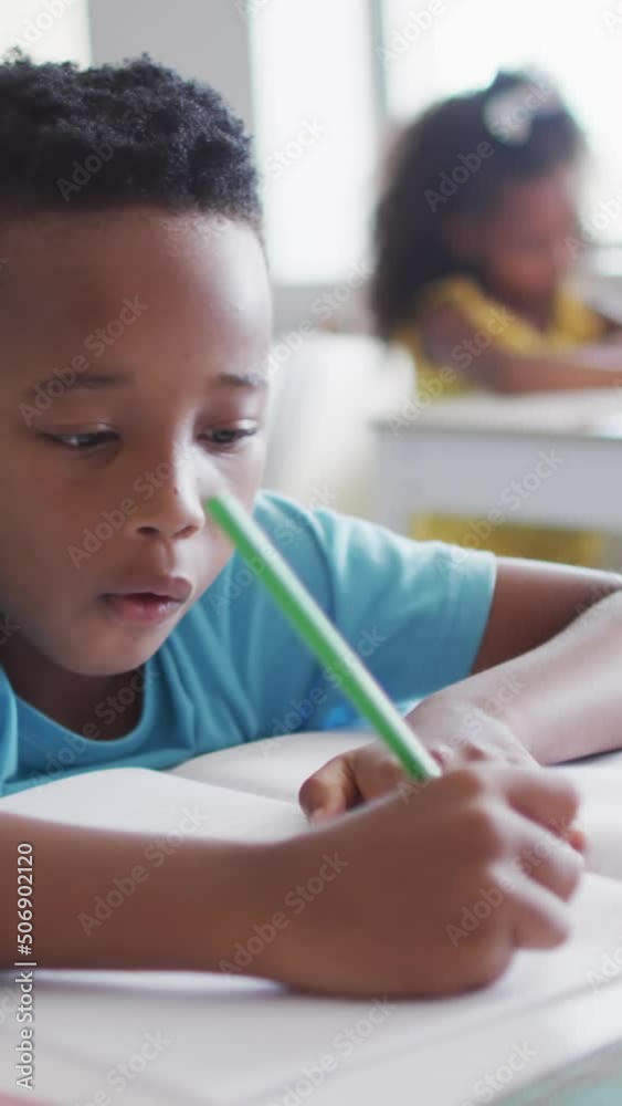 Video of focused african american boy doing lessons in classroom