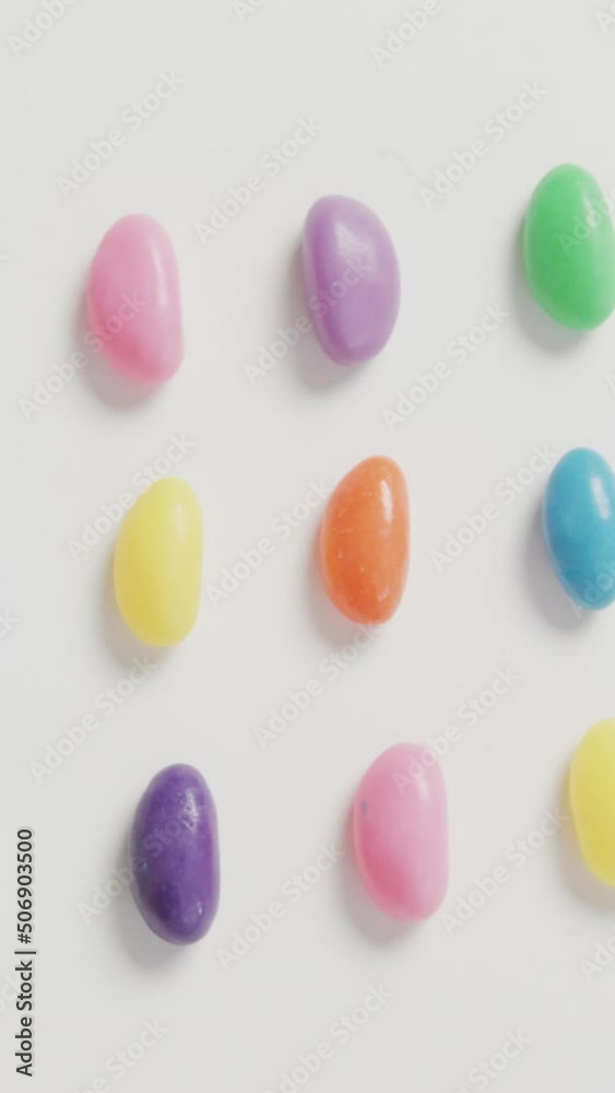 Video of overhead view of rows of multi coloured sweets over white background Video of overhead view of rows of multi coloured sweets over white background