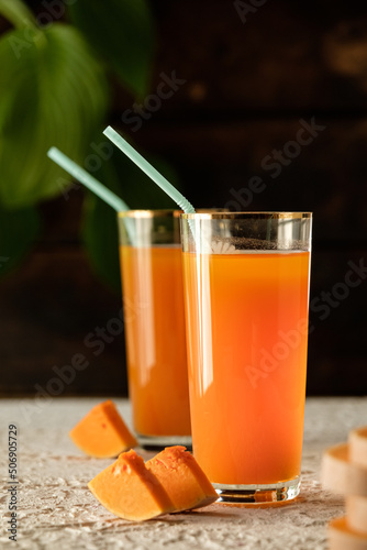 pumpkin juice with orange, orange juice in a glass with a straw, vegetable fresh in a transparent glass, two glasses with juice on a concrete table, sun rays, creative photo of a drink for a magazine,