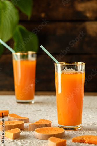 pumpkin juice with orange, orange juice in a glass with a straw, vegetable fresh in a transparent glass, two glasses with juice on a concrete table, sun rays, creative photo of a drink for a magazine,