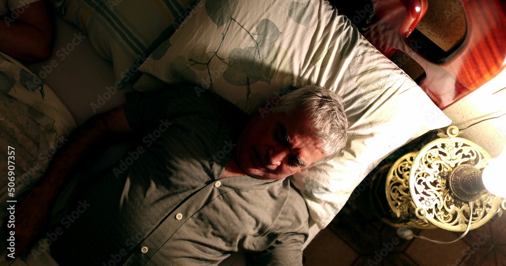 sleepless Older man suffering from insomnia turning light on