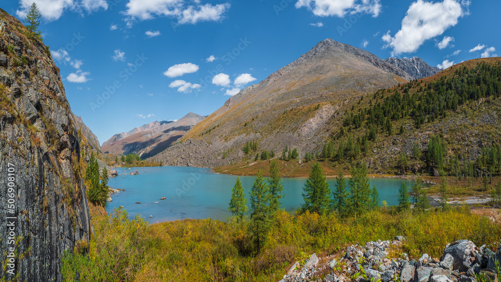 Amazing clean mountain lake in a high-altitude valley. Beautiful nature of Altai mountains. Lake in the valley, rocks and snow. Wonderful summer sunny day with gorgeous cloudscape.