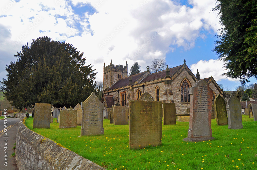 Φωτογραφία The pretty, typical Holy Trinity Church and churchyard with graves in picturesque Ashford In The Water Derbyshire U